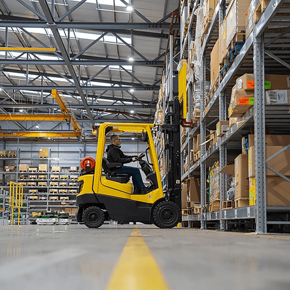 Operatore su carrello elevatore giallo in un magazzino industriale