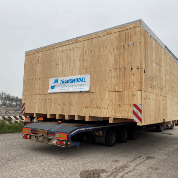 Grande cassa in legno con logo Transmodal trasportata su camion per trasporti speciali